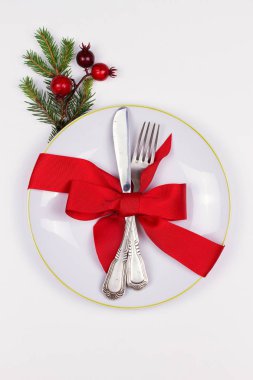 Tabak, çatal bıçak takımı, Çamın dalları, şerit ve beyaz masada kırmızı meyveler ile Noel kompozisyon. Kış tatili ve festival arka plan. Noel arifesi akşam yemeği, yılbaşı yiyecek öğle yemeği. üstten görünüm