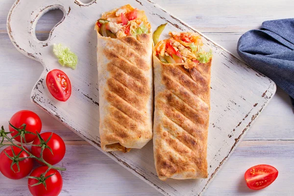 Chicken wraps with tomatoes, pickles, cabbage lettuce and onion. Tortilla, burritos, sandwiches, twisted rolls. overhead, horizontal