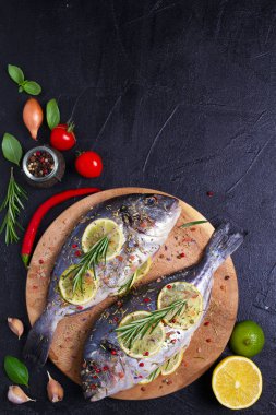 Taze çiğ kılıçbalığı veya çipura balık limon, otlar, sebzeler ve siyah arka plan üzerine baharat. Yukarıdan görüntülemek, top 
