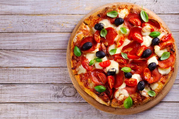 Güzel pizza ahşap tabakta. Biber, domates, peynir, zeytin ve fesleğen pizza. Yukarıda görmek, en iyi stüdyo vurdu