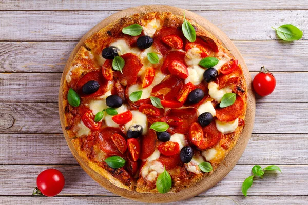 Güzel pizza ahşap tabakta. Biber, domates, peynir, zeytin ve fesleğen pizza. Yukarıda görmek, en iyi stüdyo vurdu
