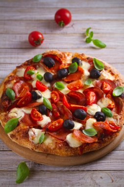  Biber, domates, peynir, zeytin ve fesleğen pizza. Güzel pizza ahşap rustik arka plan tabakta servis. dikey