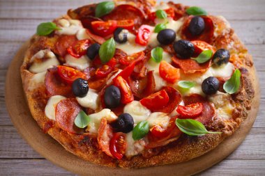  Biber, domates, peynir, zeytin ve fesleğen pizza. Güzel pizza ahşap rustik arka plan tabakta servis. Yatay