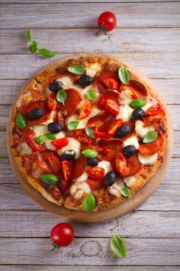  Biber, domates, peynir, zeytin ve fesleğen pizza. Güzel pizza ahşap rustik arka plan tabakta servis. Tepegöz, dikey