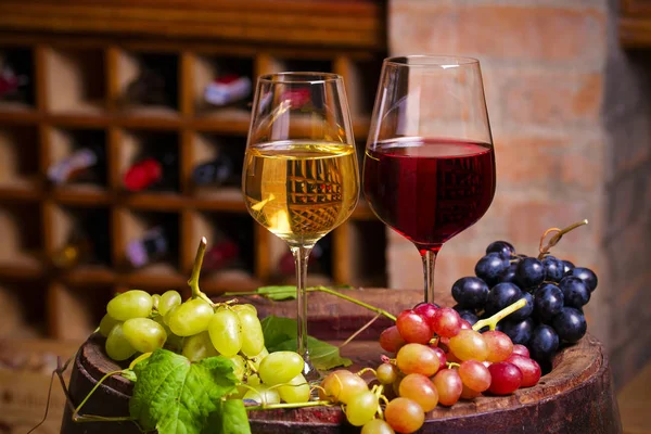 红葡萄酒和白葡萄酒 酒窖中的旧木桶上有葡萄 — 图库照片