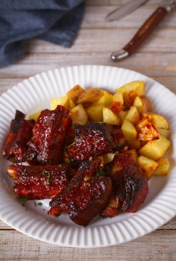 Izgara domuz kaburga ile beyaz plaka üzerinde patates uzak tut. Dilimlenmiş Barbekü kaburga kavrulmuş. dikey