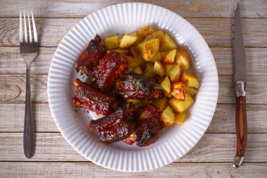 Izgara domuz kaburga ile beyaz plaka üzerinde patates uzak tut. Dilimlenmiş Barbekü kaburga kavrulmuş. Tepegöz, yatay