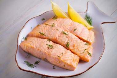 Buhar somon biftek limon ile pişirilir. Diyet menüsü. Beyaz masa beyaz tabakta. Yatay