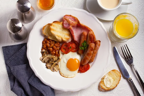 Full English or Irish breakfast with sausages, bacon, eggs, tomatoes, mushrooms and beans. Nutritious and healthy morning meal. View from above, top studio shot