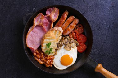 İngilizce veya İrlandalı kahvaltı sosis, pastırma, yumurta, domates, mantar ve fasulye tava üzerinde. Sabah besleyici ve sağlıklı yemek. Yukarıda görmek, en iyi stüdyo vurdu