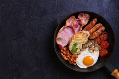 İngilizce veya İrlandalı kahvaltı sosis, pastırma, yumurta, domates, mantar ve fasulye tava üzerinde. Sabah besleyici ve sağlıklı yemek. Yukarıda görmek, en iyi stüdyo vurdu