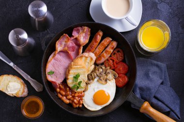İngilizce veya İrlandalı kahvaltı sosis, pastırma, yumurta, domates, mantar ve fasulye tava üzerinde. Sabah besleyici ve sağlıklı yemek. Yukarıda görmek, en iyi stüdyo vurdu