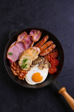 İngilizce veya İrlandalı kahvaltı sosis, pastırma, yumurta, domates, mantar ve fasulye tava üzerinde. Sabah besleyici ve sağlıklı yemek. Yukarıda görmek, en iyi stüdyo vurdu