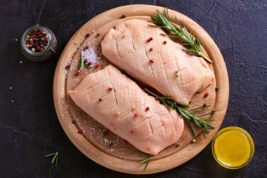 Çiğ çiğ kanatlı eti ahşap tepsi üzerinde kesti. Tatlım, biberiye ve baharatlar ile ördek göğsü