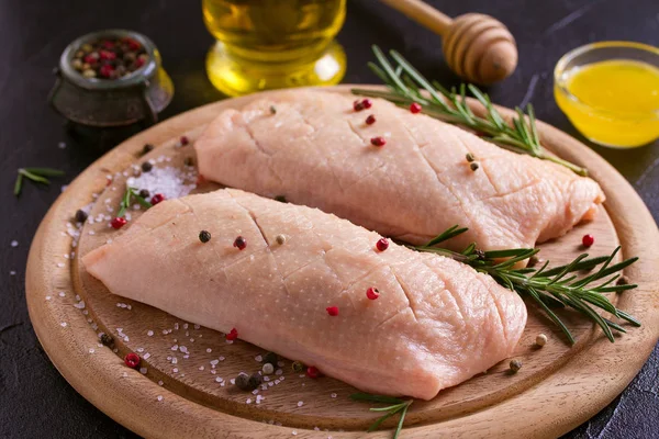 Raw uncooked poultry meat cut on wooden tray. Duck breasts with honey, rosemary and spices