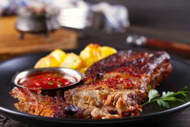 Siyah tabakta patates kızartması ile ızgara domuz yedek kaburga. Kavrulmuş dilimlenmiş barbekü kaburga