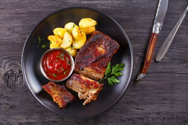 Siyah tabakta patates kızartması ile ızgara domuz yedek kaburga. Kavrulmuş dilimlenmiş barbekü pirzola. Yukarıdan görüntüle, en iyi stüdyo çekimi