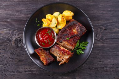 Siyah tabakta patates kızartması ile ızgara domuz yedek kaburga. Kavrulmuş dilimlenmiş barbekü pirzola. Yukarıdan görüntüle, en iyi stüdyo çekimi