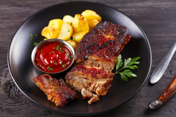 Siyah tabakta patates kızartması ile ızgara domuz yedek kaburga. Kavrulmuş dilimlenmiş barbekü kaburga