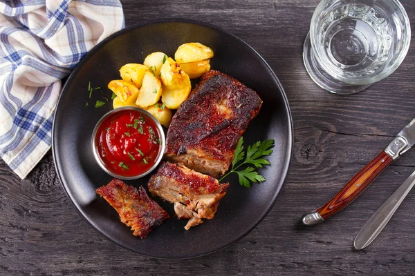 Siyah tabakta patates kızartması ile ızgara domuz yedek kaburga. Kavrulmuş dilimlenmiş barbekü pirzola. Yukarıdan görüntüle, en iyi stüdyo çekimi