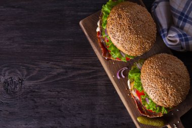 Ahşap doğrama tahtası üzerinde pastırma ile iki lezzetli ev yapımı sığır burger. Yukarıdan görüntüle, en iyi stüdyo çekimi, metin için yer. Gıda arka plan