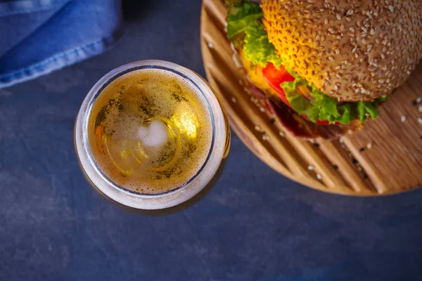 Beer and burger on wooden board for serving. Beer and food concept - Image