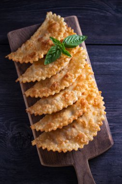 Chebureki - et ve soğan ile tavada kızarmış börek, ahşap tahta üzerinde servis. Kızarmış hamur gıda