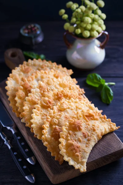 Chebureki - pan fried pies with meat and onions, served on wooden board. Fried-dough food