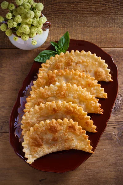 Chebureki - pan fried pies with meat and onions on plate. Fried-dough food. Overhead, vertical - Image