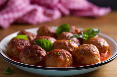 Domates soslu köfte, tahta masa üzerinde kasefelik ile süslenmiş