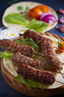 Pide, sebze ve yoğurt soslu servis tahtasında kuzu kebaplar