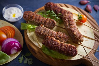 Pide, sebze ve yoğurt soslu servis tahtasında kuzu kebaplar