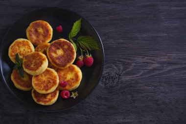 Siyah plaka üzerinde süzme peynir krep. Syrniki ve ahududu