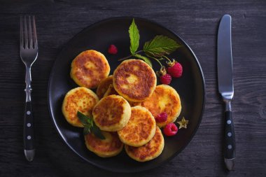 Siyah plaka üzerinde süzme peynir krep. Syrniki ve ahududu