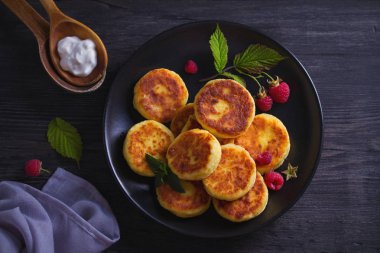 Siyah plaka üzerinde süzme peynir krep. Ekşi Krem ile syrniki