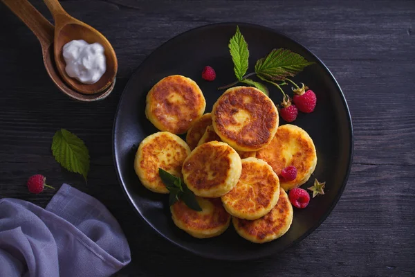 Siyah plaka üzerinde süzme peynir krep. Ekşi Krem ile syrniki