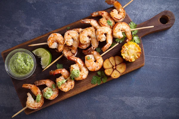 Skewered shrimps with garlic butter sauce served with cilantro and lime on serving board