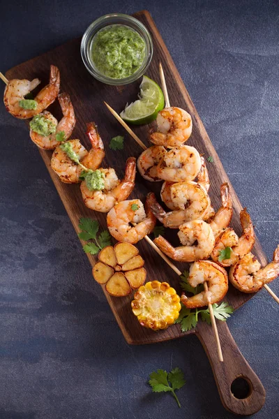 Skewered shrimps with garlic butter sauce served with cilantro and lime on serving board