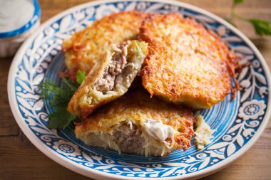 Et dolu patateskrep. Sebze börek mavi tabak ve ekşi krema veya yoğurt üzerinde et ile doldurulmuş
