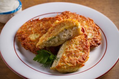 Patates Krep Köy Peyniri ile Doldurulmuş. Beyaz tabak, ahşap masa üzerinde ev yapımı sebze börek