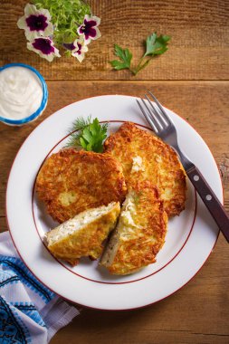 Patates Krep Köy Peyniri ile Doldurulmuş. Beyaz tabak, ahşap masa üzerinde ev yapımı sebze börek