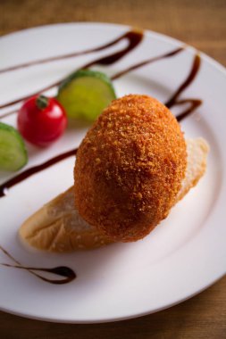 Tavuk Kiev ve beyaz plaka, ahşap arka plan üzerinde sebze. Ekmekli tavuk göğsü otlar ve tereyağı ile doldurulmuş