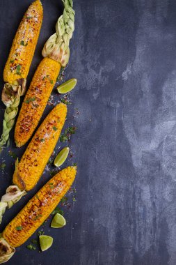 Parmesan peyniri, kırmızı biber, tuz, kişniş ve kireç ile ızgara tatlı mısır koçanı üst görünümü. Kopyalama alanı