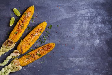 Parmesan peyniri, kırmızı biber, tuz, kişniş ve kireç ile ızgara tatlı mısır koçanı üst görünümü. Kopyalama alanı