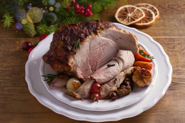 Beyaz tabakta pişmiş jambon, Noel süslemeleri ile masa. Noel arifesi için yemek. Kış sezonu tatil gıda