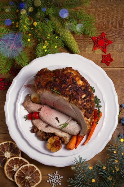 Baked ham on white plate, table with Christmas decorations. Dish for Christmas Eve. Winter season holidays food