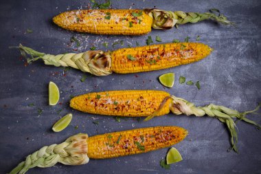Parmesan peyniri, paprika, tuz, kişniş ve gri zemin üzerine limon serpiştirilmiş ızgara mısır koçanı. Masraflar, metin için yer