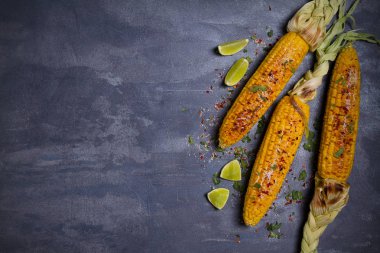 Parmesan peyniri, paprika, tuz, kişniş ve gri zemin üzerine limon serpiştirilmiş ızgara mısır koçanı. Masraflar, metin için yer