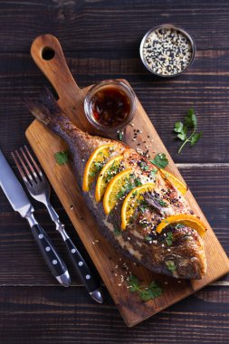 Turuncu zencefilli deniz balığı, susam tohumları ve kişniş serpiştirilmiş. Soya portakal sosu. Tepedeki dikey resim