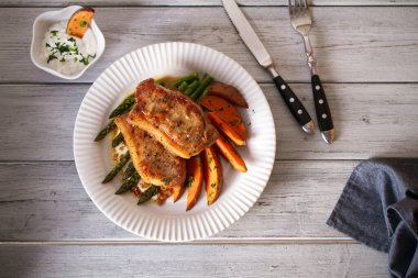 Kuşkonmaz, tatlı patates ve yoğurt soslu domuz pirzolası. Yatay görüntünün üstünde